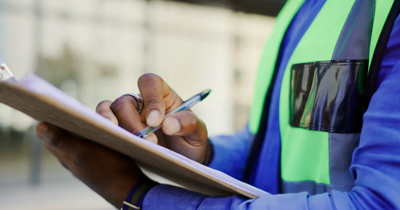 Hands writing on a clipboard on a work site