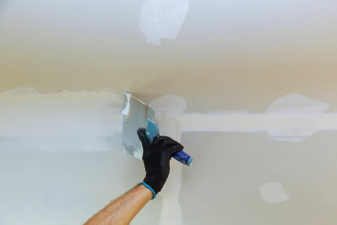 A taping knife skimming compound flat over a wall patch