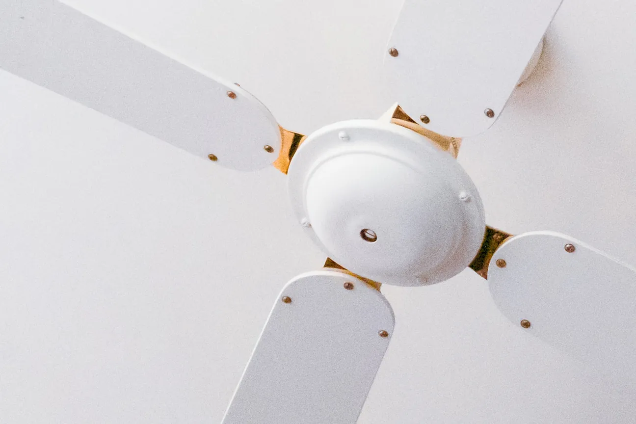 A white ceiling fan with brass fittings hanging from a ceiling