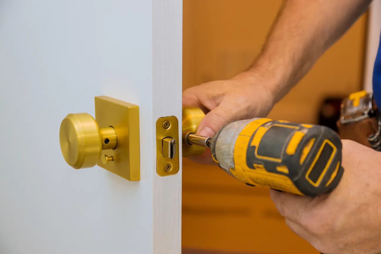 A gold lock set driven into a white door with a drill
