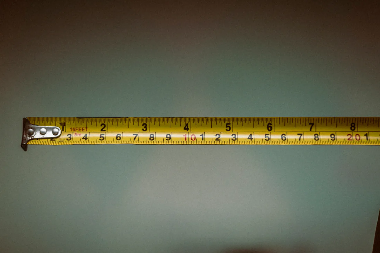 A steel tape measure pulled out along a plain wall