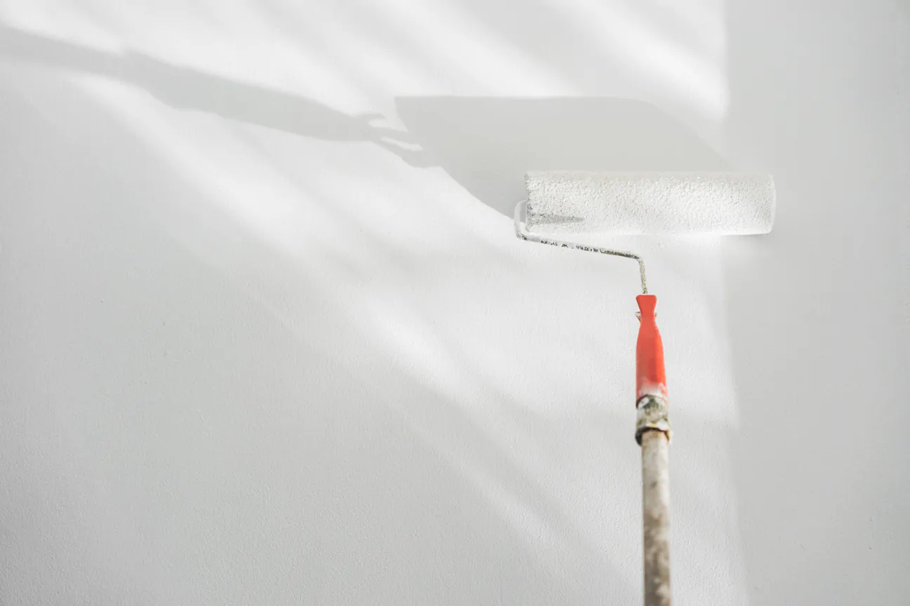 A roller laying a fresh white coat across a wall